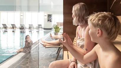 Kinder winken unterhaltsam durch die Glasscheibe beim Schwimmbad