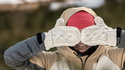 Person mit roten Mütze und weißen Handschuhen zeigt Daumen nach oben