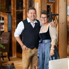 Lächelndes Paar in traditioneller Tracht in einem gemütlichen Holzinterieur