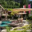 Hotelpool mit Liegestühlen und Sonnenschirmen in grüner Alpenlandschaft
