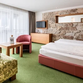 Gemütliche, großzügige Suite mit Naturmaterialien, Doppelbett und gemütlicher Lounge mit Couch, Tisch und Sitzgelegenheit und gepackter Wellnesstasche