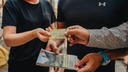 Person übergibt Nationalpark Sommercard an andere Person mit Wander- und Bikekarte