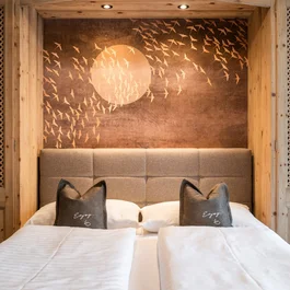 Cozy double bed with wood paneling and wall art of flying birds