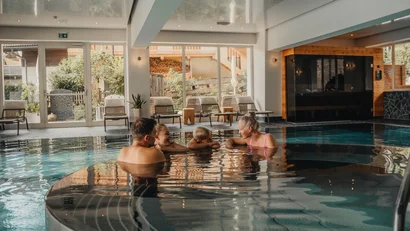 Familie entspannt im Innenpool eines modernen Wellnesshotels