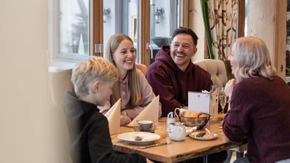 Familie lacht und genießt gemeinsame Mahlzeit am gedeckten Esstisch